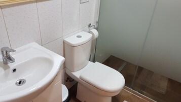 Un baño con lavamanos blanco, inodoro y zona de ducha.