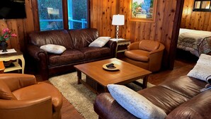 A cozy living room with leather sofas, a wooden coffee table, and a TV. - "Driftwood Island Retreat" Spectacular View, Private Waterfront on James Point. (Vashon)