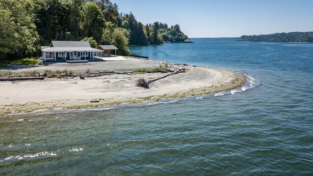 A coastal property with a large house and a smaller structure, a sandy beach, and a clear view of the water. - "Driftwood Island Retreat" Spectacular View, Private Waterfront on James Point. (Vashon)