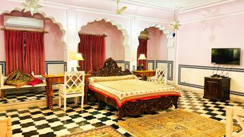 A traditional room with a bed, two chairs, a table, a television, and decorative elements like star-shaped lights and patterned rugs.