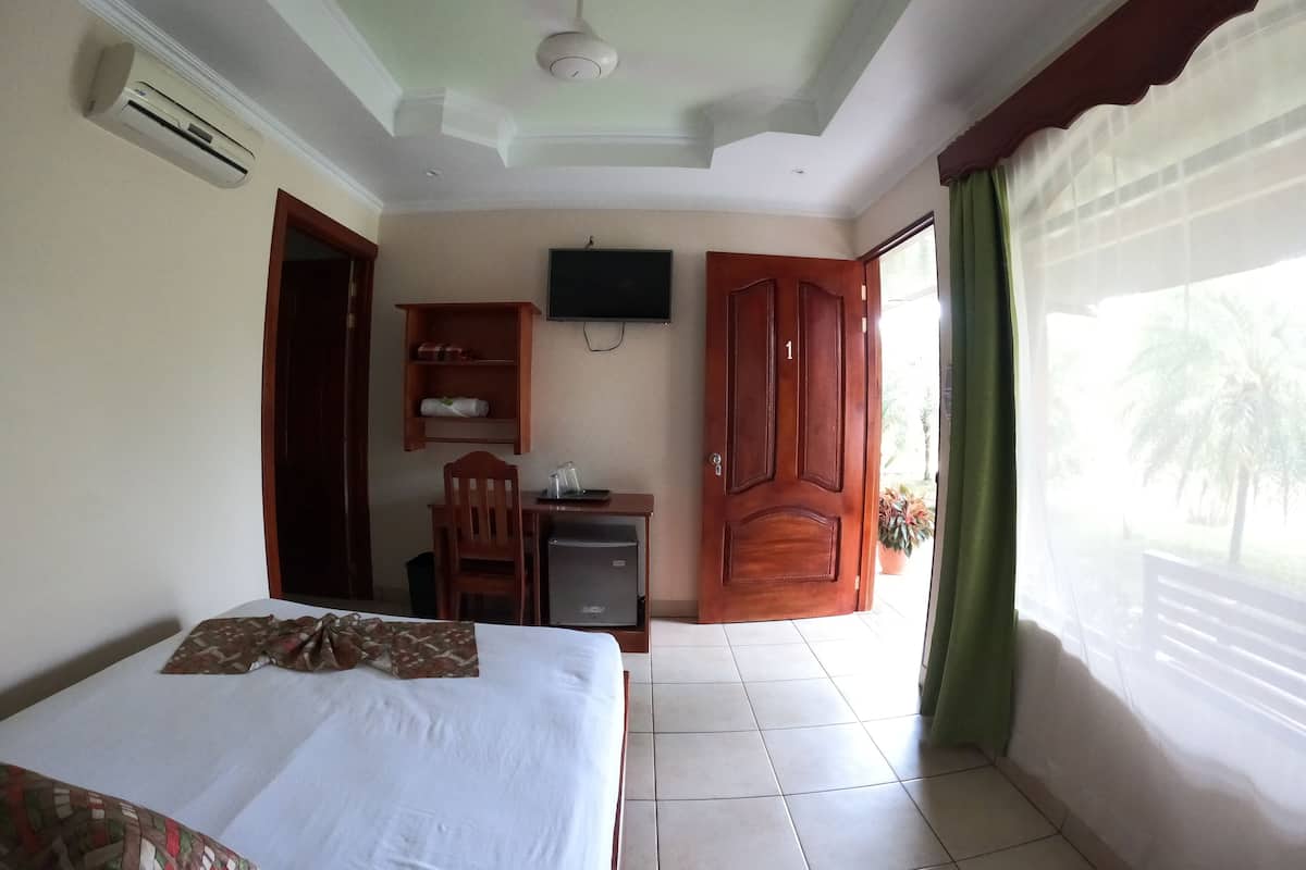 A hotel room with a bed, a desk, a television, and a door.