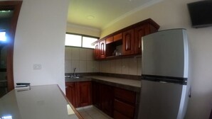 Eine Küche mit Holzausstattung, einem Edelstahl-Kühlschrank und einer gefliesten Spritzschutzwand.