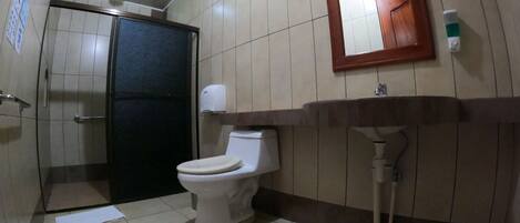 A bathroom with a toilet, sink, mirror, and a door.