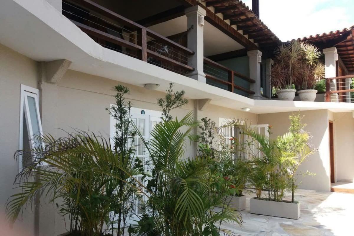 A courtyard with potted plants, a tiled floor, and a building with a balcony.