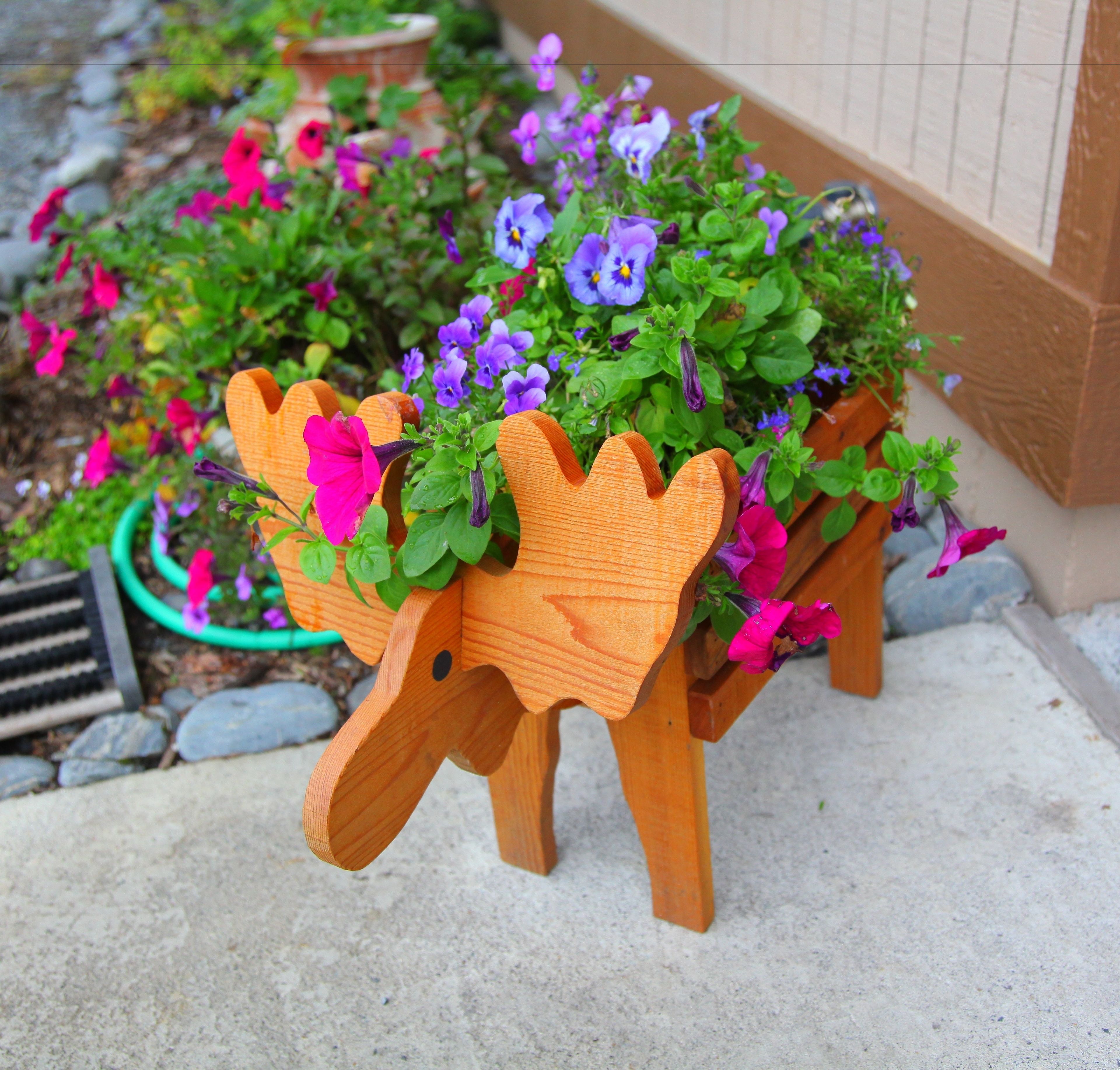 Una jardinera de madera con forma original, llena de flores de colores.