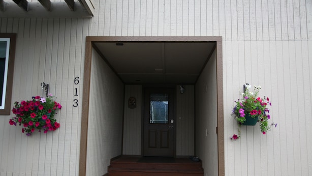 Une entrée de maison avec une porte en bois, des marches et des jardinières.