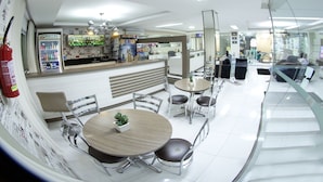 A modern hotel lobby with a reception desk, seating area, and a bar. - Hotel Sambakia (Realeza)