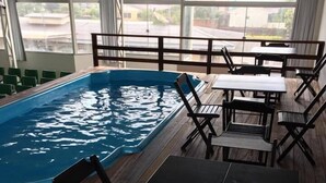 A poolside area with a rectangular pool, wooden deck, and outdoor seating. - Hotel Sambakia (Realeza)