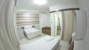 A hotel room with two beds, a sofa, a bathroom with a shower, and a curtain. - Hotel Sambakia (Realeza)