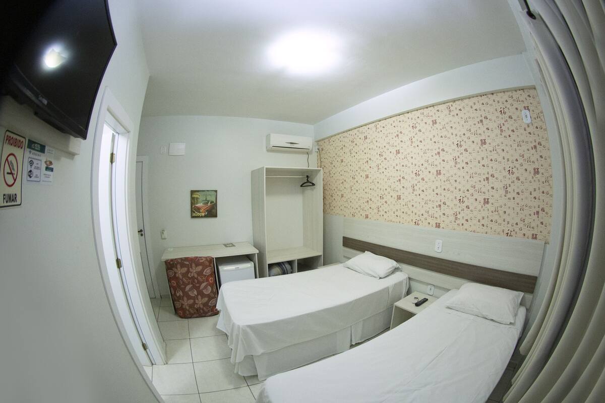 Une chambre d’hôtel avec deux lits, un bureau, une armoire et un téléviseur.