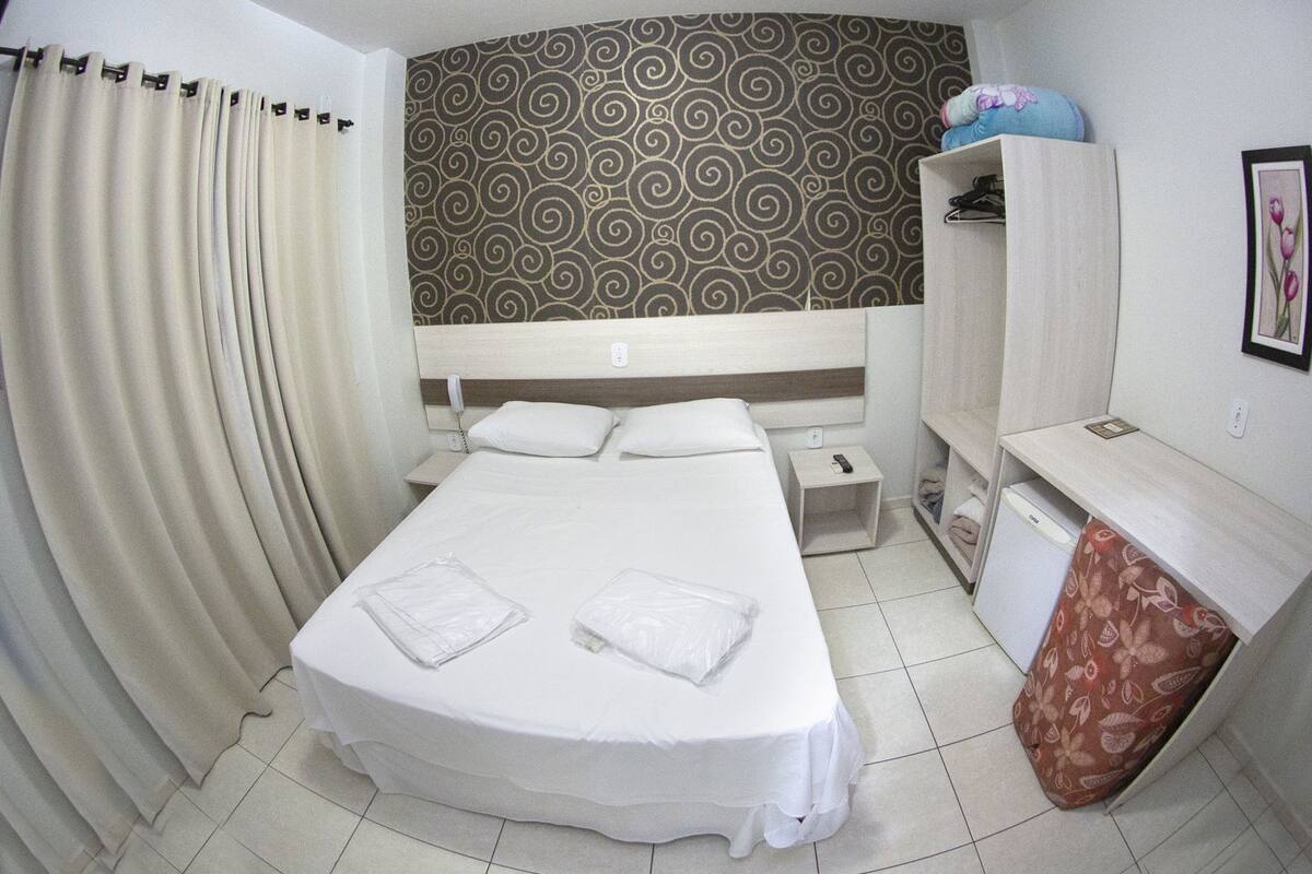 Une chambre d’hôtel avec un lit, un bureau, une armoire et un mur décoré de motifs.