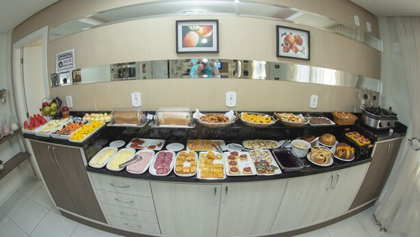 A buffet with various food items and a sign indicating the use of a mask. - Hotel Sambakia (Realeza)