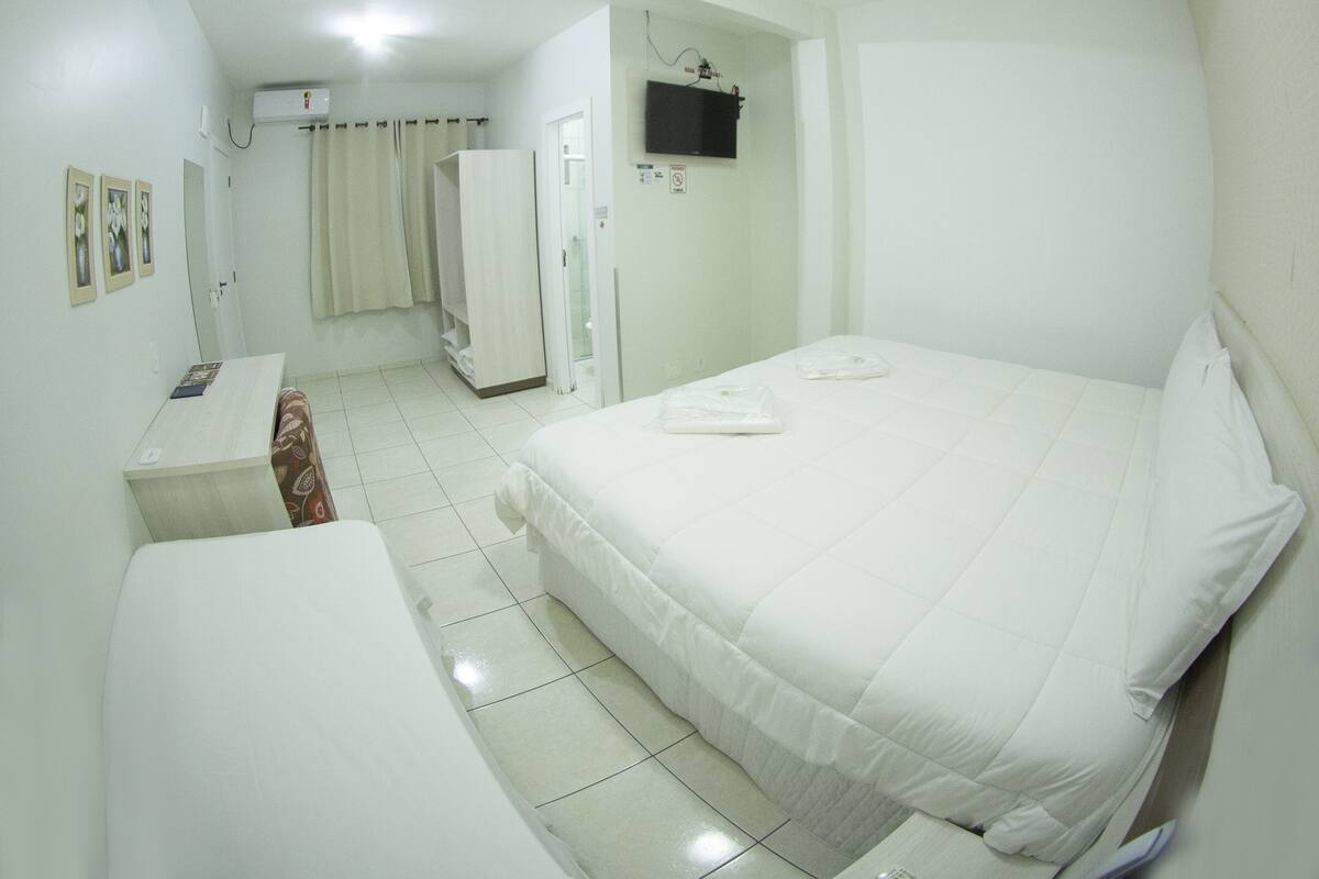 Une chambre d’hôtel comprenant un lit, un bureau, une chaise, une armoire et un téléviseur.
