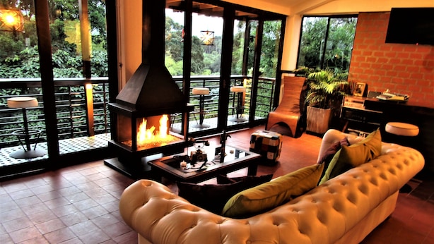 A modern living room with a large sofa, a fireplace, and a view of the outdoors. - Hotel Bambu Inn (Salento)