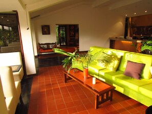A living room with a bright green sofa, a wooden coffee table, and a large plant. - Hotel Bambu Inn (Salento)