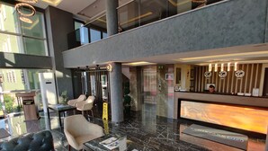 Vestíbulo de hotel con recepción, zona de estar y ascensores.