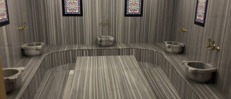 A modern bathroom with a curved layout, multiple sinks, and decorative tiles.