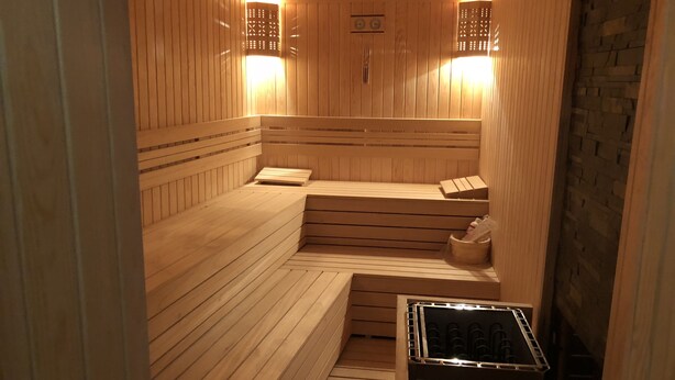 Una sauna con bancos de madera, un banco con una toalla y un calentador.
