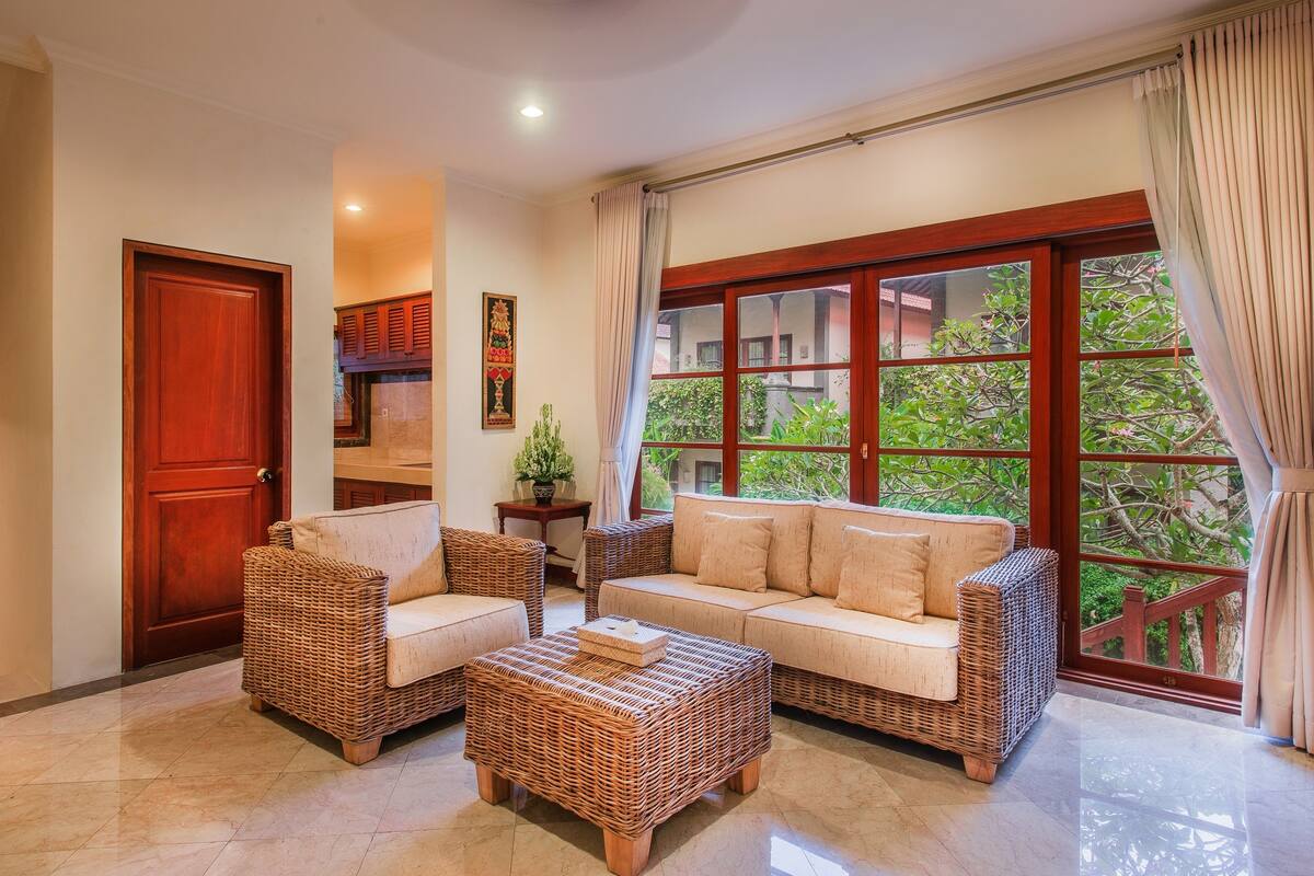 A spacious living area with a large window, wicker furniture, and a door.
