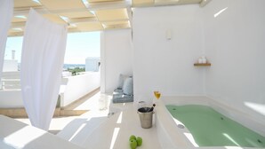 A bright, white room with a green bathtub, a small table with a bucket and apples, and a view of the city. - Blue Sky Summer (Naxos)