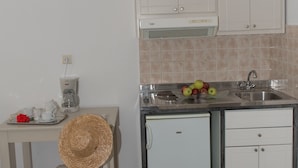 A compact kitchen with a sink, a coffee maker, and a small refrigerator. - Blue Sky Summer (Naxos)