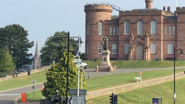 Un edificio histórico con una torre destacada y una estatua frente a él.