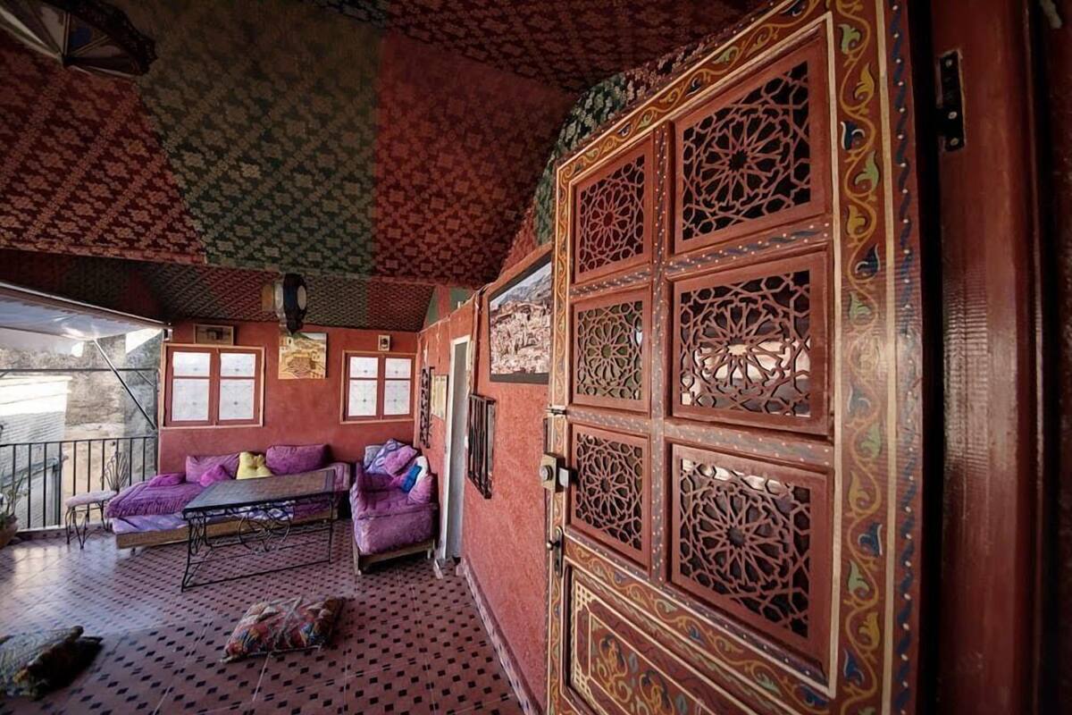 A room with a patterned ceiling, a large ornate wooden door, and a sofa with cushions.