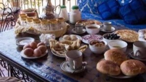 A dining table with various dishes, including bread, pastries, and a teapot. - Dar  El Amane Abqari (Fes)