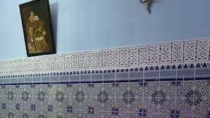 A bedroom with a patterned tile headboard, a bed with white linens, and a wooden nightstand. - Dar  El Amane Abqari (Fes)
