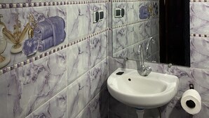 A bathroom with marble tiles, a sink, a mirror, and a toilet paper holder. - Dar  El Amane Abqari (Fes)