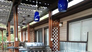 An outdoor kitchen area with a grill, bar counter, and hanging blue pendant lights. -  Miles to VIR, Caesar's VA Casino,  Martinsv'l , S.Boston, Priv. Pool seasonal! (Sutherlin)