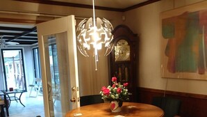 A dining area with a round wooden table, four chairs, a vase with flowers, a wall clock, and a ceiling light fixture. -  Miles to VIR, Caesar's VA Casino,  Martinsv'l , S.Boston, Priv. Pool seasonal! (Sutherlin)