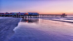 A pier extending into the water with buildings on stilts. - Coastal Escape Oceanfront Corner Unit with Heated Pool and Resort Amenities (Cocoa Beach)