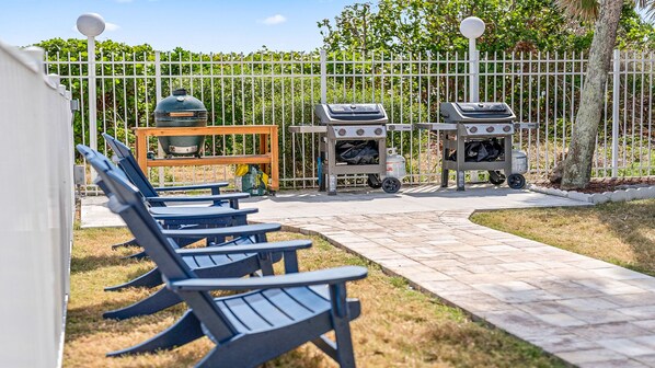 Un patio al aire libre con estación de parrillada, zona de estar y un camino.