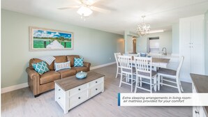 A living room with a brown leather sofa, a dining table with chairs, and a ceiling fan. - Oceanfront Escape Newly Renovated and Just Steps from the Pier (Cocoa Beach)
