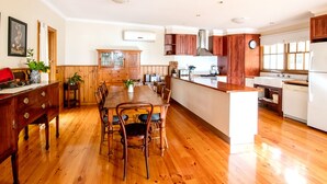 A spacious kitchen with wooden flooring, a central island, and a dining area with wooden chairs.