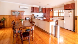 A spacious kitchen with wooden cabinets, a central island, and a dining area with wooden chairs.