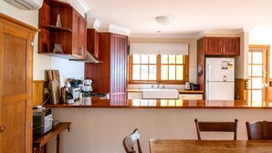 A kitchen with wooden cabinets, a central island, a refrigerator, and a window with blinds.
