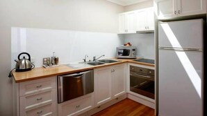 A modern kitchen with white cabinets, stainless steel appliances, and a wooden countertop. - Bella Loft:  A studio apartment in the heart of Woodend. (Woodend)