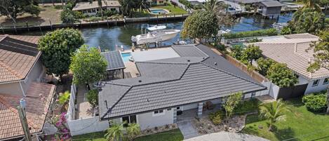 Um bairro residencial com uma casa de telhado apaleçado, uma piscina e um cais com barcos.