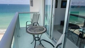 Un balcon avec une table et des chaises, offrant une vue sur l’océan.