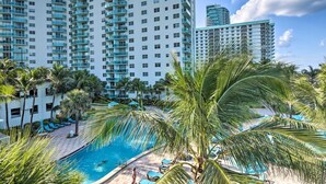 Un hôtel doté d’une piscine entourée de palmiers et de chaises longues.