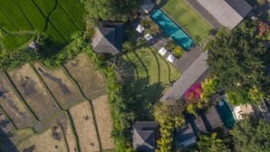 Vue aérienne d’une propriété comprenant une piscine, plusieurs bâtiments et de vastes espaces verts environnants.