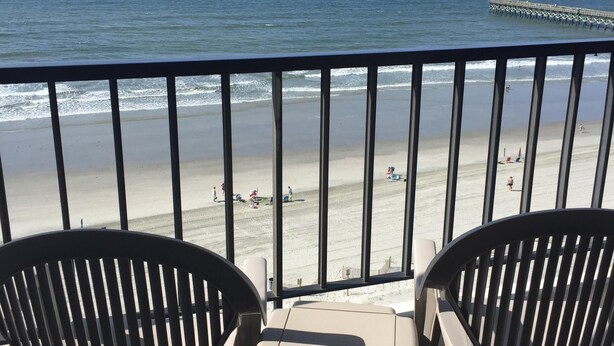 A balcony with two chairs facing a beach, a pier in the distance, and the ocean. - INCREDIBLE OCEANFRONT VIEWS/3 BR, 3 Bath Luxury Condo/Sea Marsh I (North Myrtle Beach)