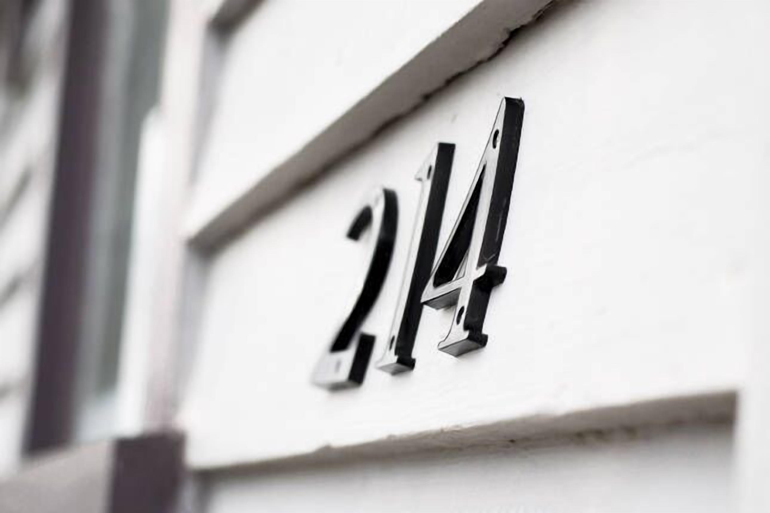 Lähikuva valkoisesta rakennuksesta, jossa on musta kyltti, jossa lukee numero '214'.