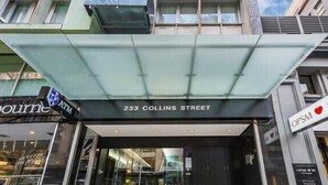 The entrance to a building with a sign reading "233 Collins Street" and an "OPS" sign with a heart symbol. - Nice city stay at Collins apartment (Melbourne)