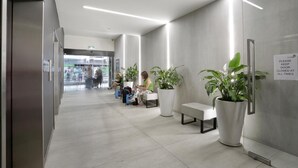 A modern waiting area with seating and potted plants, a sign requesting to keep the door closed, and a view of the outside through a glass door. - Nice city stay at Collins apartment (Melbourne)