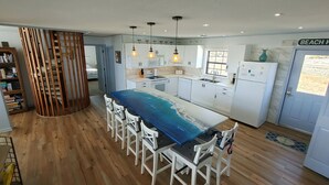 Cocina moderna con muebles blancos, una isla central con un backsplash de temática marina en azul, e iluminación colgante.
