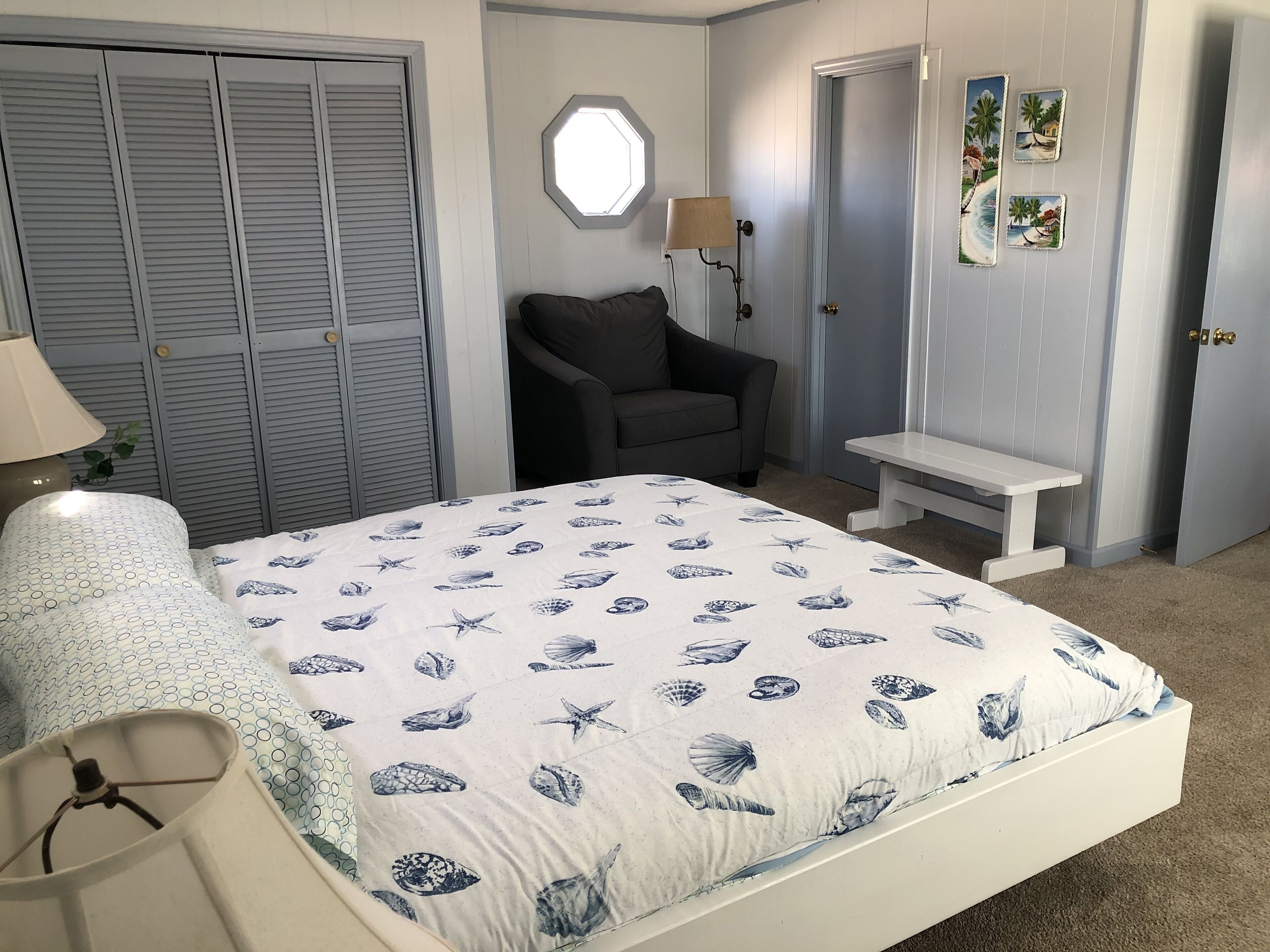 A bedroom with a bed, a chair, a desk, and a wardrobe.