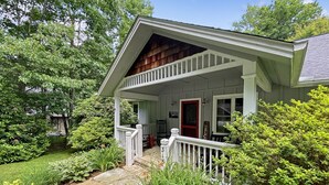 A two-story house with a front porch, a red door, and a stone pathway leading to the entrance. - Just the Right Size. Exactly Enough | Highlands Haven (Highlands)
